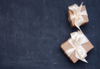 Two Boxes in Eco Paper on the Darck Blue Wooden Table. Top view. Parcels or gifts Tied with Satin White Ribbon.