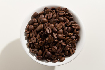 coffee beans seed. Top view of grains in a bowl. White background.