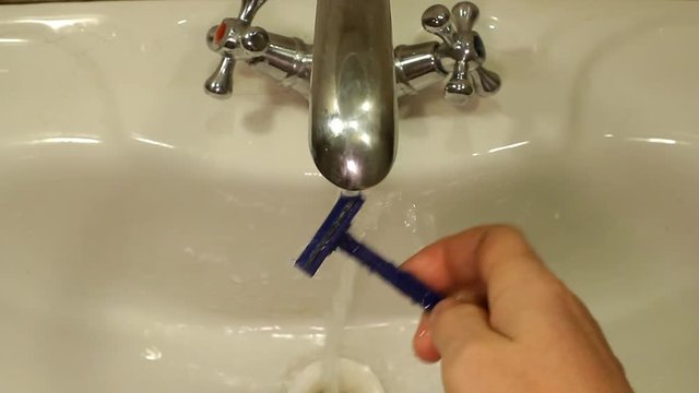 man rinses shaving machine after shaving