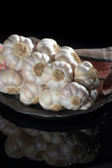String of french pink garlic on old tin plate on black background