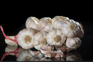 String of french pink garlic on old tin plate on black background