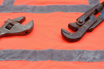 Adjustable and pipe wrenches against the background of an orange signal worker shirt
