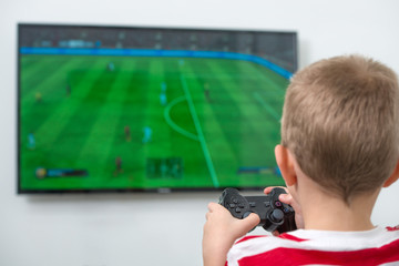 Boy with joystick playing video game at home.