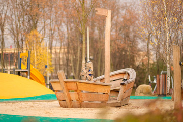 Modern equipped kids playground in sunny day. Wood boat on sand