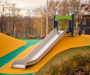 Modern equipped kids playground in sunny day. Metal slide from hill