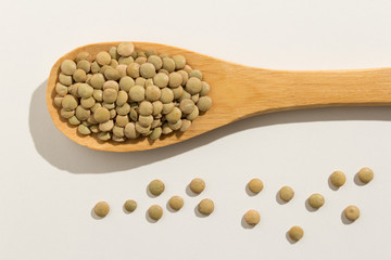 Lentil legume. Healthy grains on a wooden spoon. White background.