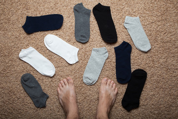 Chaos of socks is like finding a pair. Legs against the background of scattered socks.
