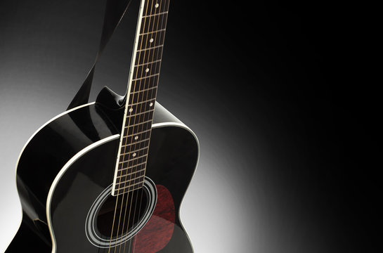 Black acoustic guitar on a black background