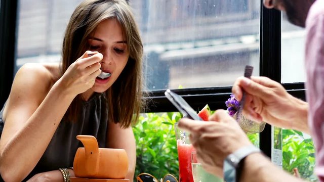 Young couple during lunch in cafe, man using smartphone
