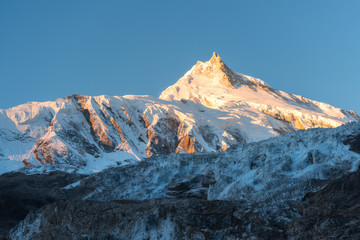 Beautiful view of snow-covered mountain at colorful sunrise in Nepal. Landscape with snowy peaks of Himalayan mountains, glacier and blue sky in the morning. Amazing Manaslu. Himalayas. Nature 
