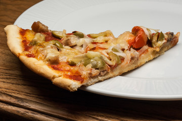 Slice of pizza on plate (meat, olives, cheese, tomato, onion)