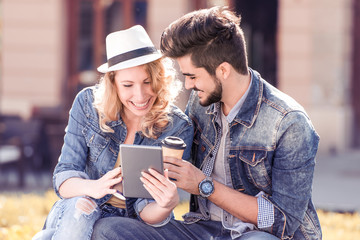 Couple using tablet and drink coffee to go.