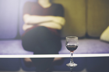 Alcoholic woman is pouring wine into a glass