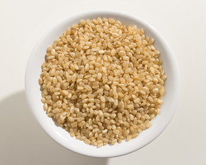 Whole Short Grain Rice Seed. Top view of grains in a bowl. White background.