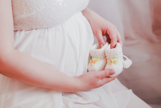 A pregnant woman holds the little booties for your unborn baby