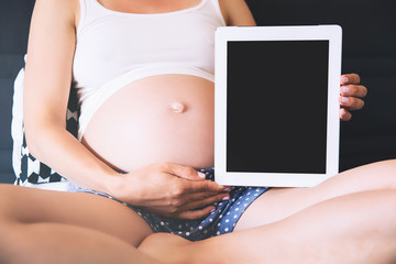 Pregnant woman showing blank digital tablet screen