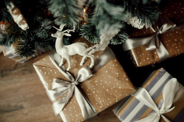Christmas gift boxes under the fir tree. Deer toy on a box