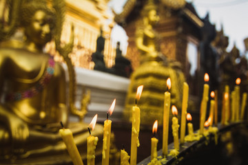 Naklejka na ściany i meble Candle light in front of buddha image.
