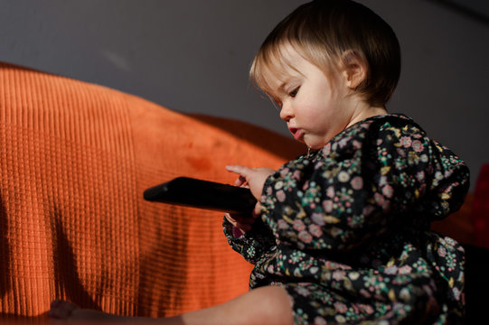 girl on an orange couch with remote control