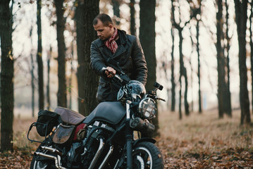 Fototapeta na wymiar Man and old custom cafe-racer Motorcycle on forest 