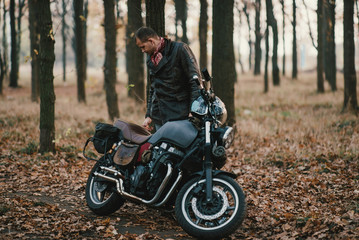 Fototapeta na wymiar Man and old custom cafe-racer Motorcycle on forest 