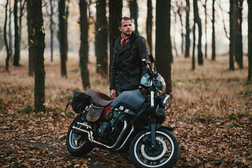 Obraz na płótnie Canvas Man and old custom cafe-racer Motorcycle on forest 