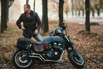 Man and old custom cafe-racer Motorcycle on forest 