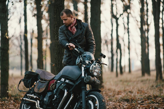 Man and old custom cafe-racer Motorcycle on forest 