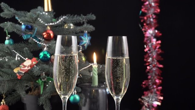 Glasses with champagne against holiday candle