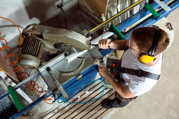 Worker in the workshop cuts the pvc profile with circular saw