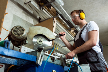 Worker in the workshop cuts pvc profile