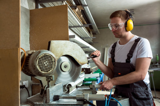 Worker in the workshop cuts pvc profile