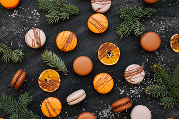 Pattern with oranges, macaroons, chocolate and fir branches on a black background. flat lay,  top view,