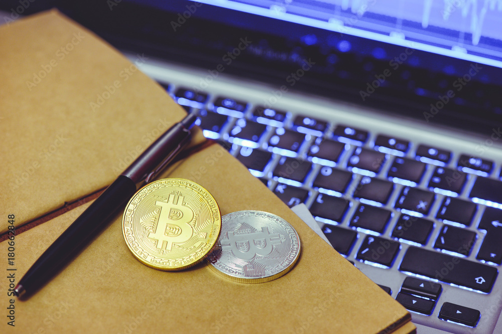 Fototapete Bitcoin is a gold coin in the notebook of a business man against a computer background and an increasing graphics. The concept of virtual crypto currency