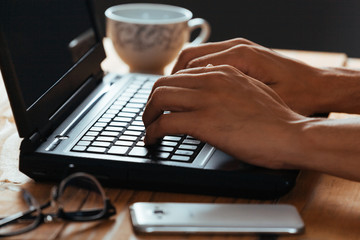 Close-up of hands of man typing on a laptop