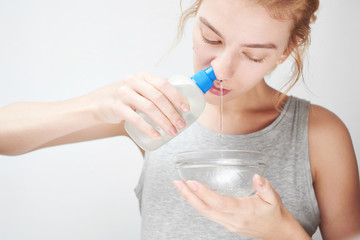 Treatment and prevention of the common cold. The girl washes out the nose with saline