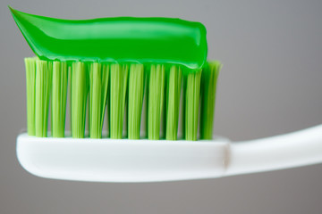 Green toothpaste on the brush closeup