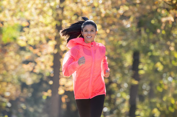 attractive and happy runner woman in Autumn sportswear running a
