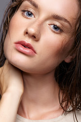 Obraz premium Beauty portrait of young woman. Brunette girl with bright blue eyes and day female makeup on gray background