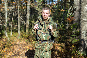 Fototapeta premium Tourist in camouflage clothes walking in the autumn forest