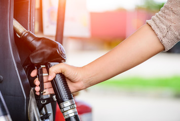 Closeup of woman  hand holding a fuel pump at a station.