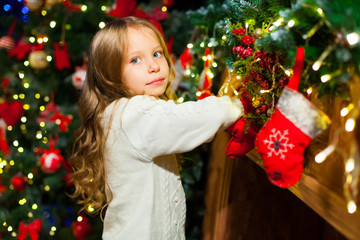 Cute toddler girl checking her Christmas stocking under a beauti