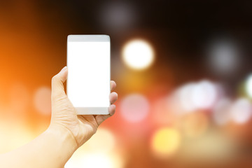 Man hand holding the white smartphone on GOLDEN light bokeh background.