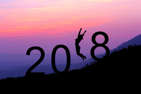 Silhouette young woman jumping over 2018 years on the hill at sunset.