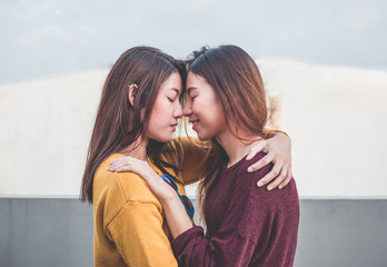 Asia lesbian LGBT Couple hug and nose kiss on rooftop of building with happiness moment.