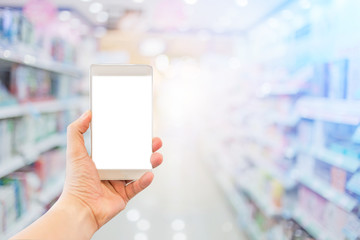 blur image background of supermarket in shopping mall with hand hold blank screen smartphone for your text