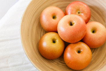 red apple in wooden bowl on color checker fabric with moring light on wooden table