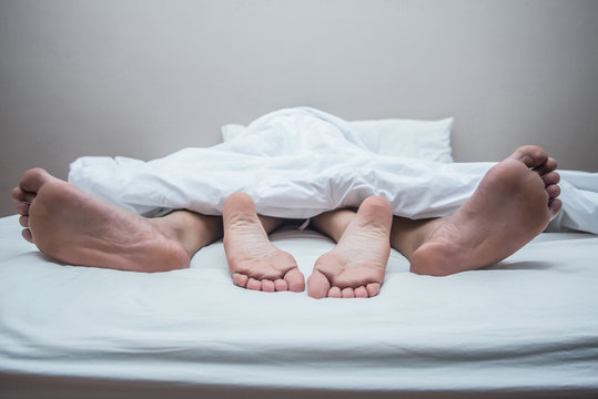 Close up legs of couple in bed.