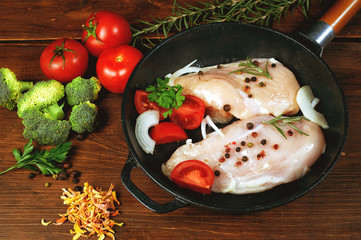 Raw chicken breast with vegetables ingredients in a cast iron skillet. Cooking