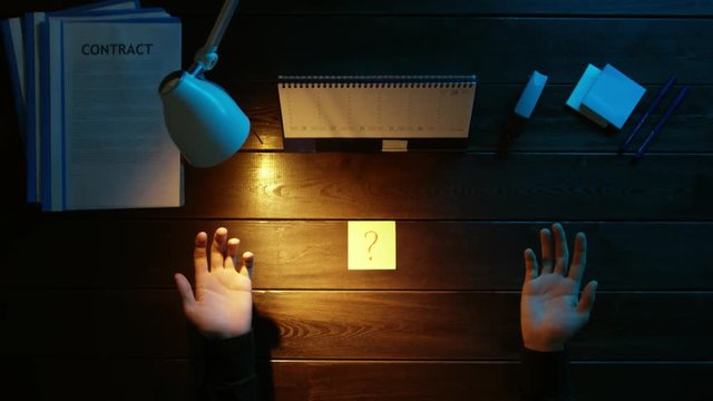 A man is sitting at an office desk and using a phone.
